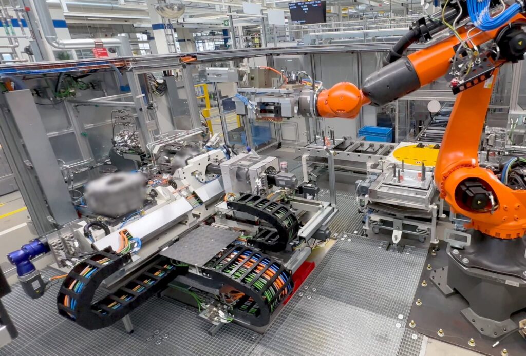 An industrial robot arm assembles components on an automated production line in a modern factory setting.