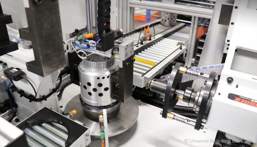 A close-up view of industrial machinery in a factory, showing metal parts, rollers, and automation components used in manufacturing processes.